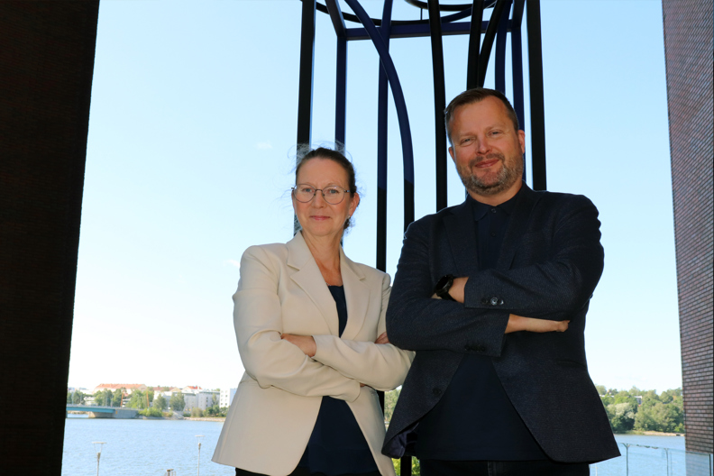 Kaksi henkilöä metallisen taideteoksen edessä